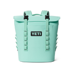 Mint green Yeti Hopper M20 Backpack Soft Cooler featuring a prominent black Yeti logo, a roll-top magnetic closure, and black buckles on its shoulder straps along with side webbing loops