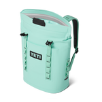 Product photo of a seafoam green Yeti Hopper M12 cooler backpack featuring the MagShield Access magnetic closure, a front pocket with the YETI logo, and padded shoulder straps on a black background