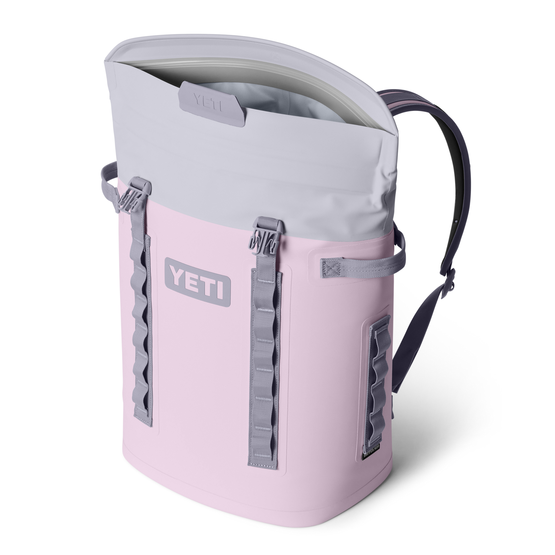 A light pink and grey YETI Hopper M20 backpack cooler with an open magnetic top and side attachment straps, presented on a black background