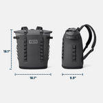 Product photograph of a dark grey Yeti Hopper M20 soft backpack cooler in front and side views against a plain background, featuring its lighter grey roll-top closure, prominent Yeti logo, and dimensions 18.1 inches by 9.9 inches