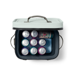 An overhead studio shot of an open light mint-green and dark grey portable cooler filled with nine colorful purple and teal cans, one green Waterloo Guava Berry sparkling water can, and a blue Yeti ice pack