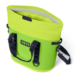 YETI Hopper M20 cooler bag in vibrant fluorescent green with its open top revealing the waterproof MagShield Access and equipped with black grab handles and a shoulder strap against a black studio background