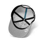 Grey Melin snapback cap featuring a perforated white interior with a subtle grey marble pattern, black branded crisscross straps, a blue 'DESIGNED IN CALIFORNIA' tag, and a textured brim with a white rubberized Melin logo