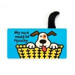 Children's board book illustration of a cartoon dog with brown ears, an orange eye patch, and red tongue sticking out from a yellow woven basket on a bright blue page featuring the text "My nose would be squashy" and a fuzzy black tail emerging from the top