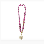 A handcrafted pink black and white braided lanyard featuring ornate gold and pink beads with a sparkling gold sunburst charm