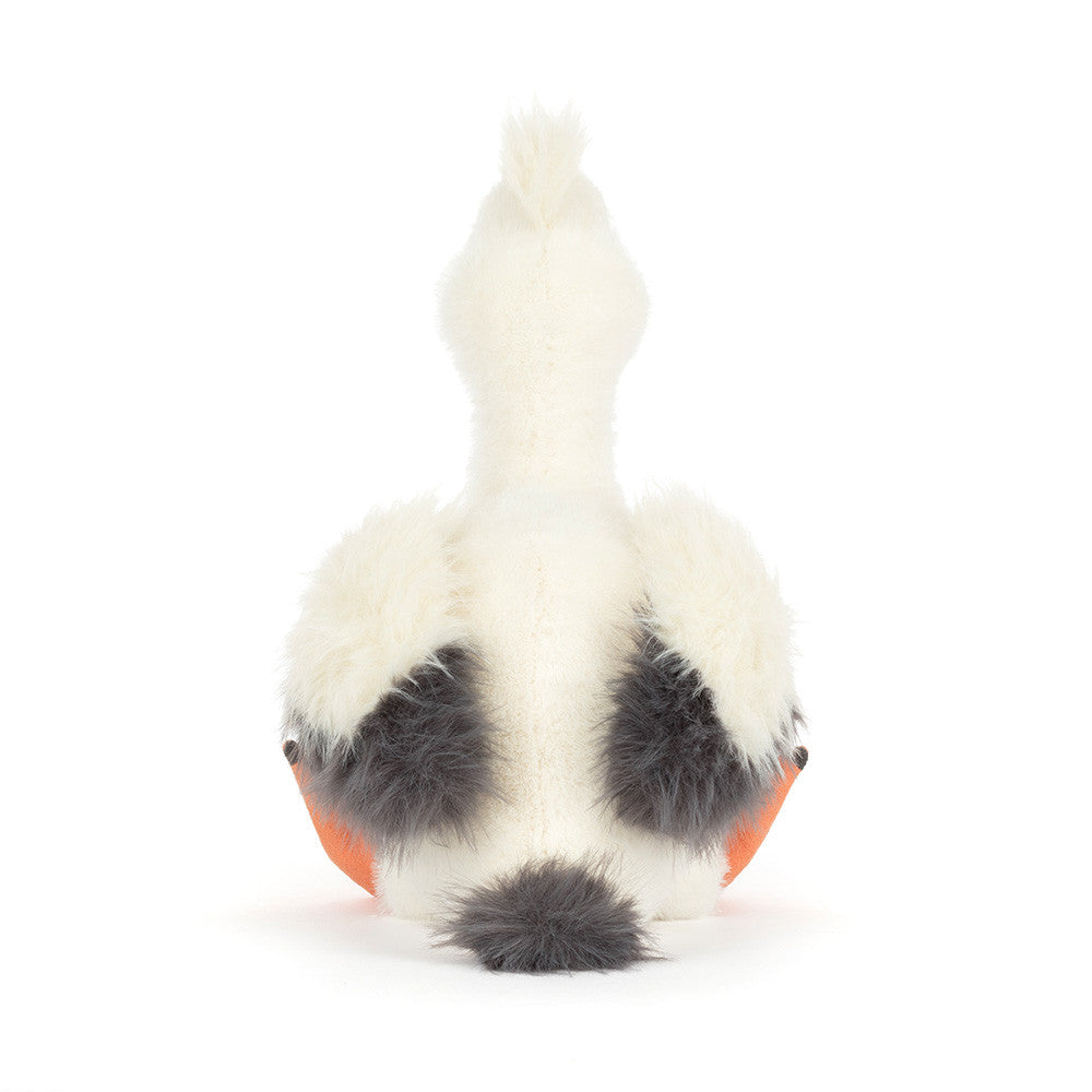 Plush toy white pelican seen from the back featuring dark grey fluffy wing patches a small tail and vibrant orange webbed feet