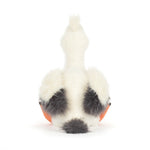 Jellycat plush pelican seen from the back against a white studio background with soft cream-colored fur, charcoal grey wing tips, and a small tufted head crest