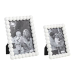 Digital photograph of two white beaded Mudpie photo frames, one larger square and one smaller upright, displaying black and white portraits of a mother with a baby and a family of three, all against a plain white background