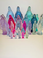 Collection of translucent colored glass Virgin Mary statues with small gold crowns