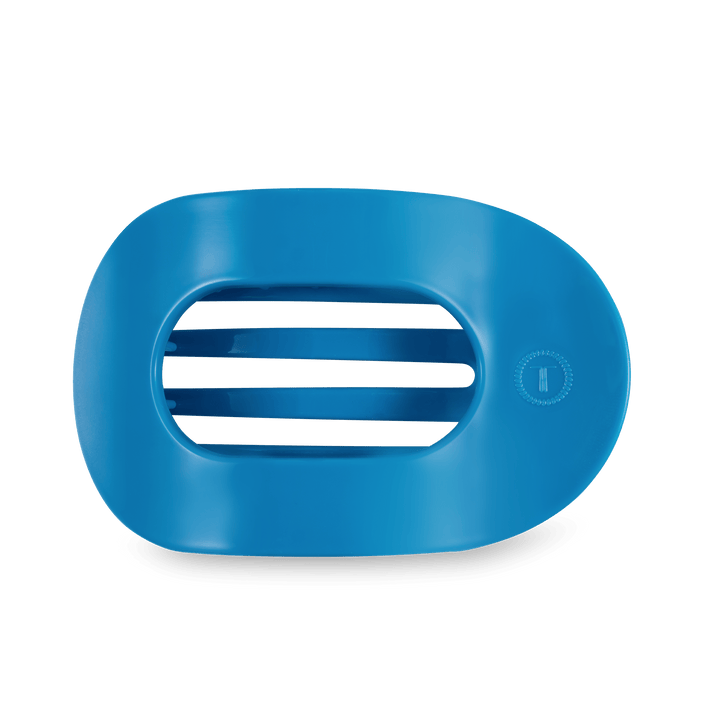 Studio shot of a matte blue oval object featuring four horizontal central slits and a small embossed circular logo with a letter T on the right, presented against a dark green background