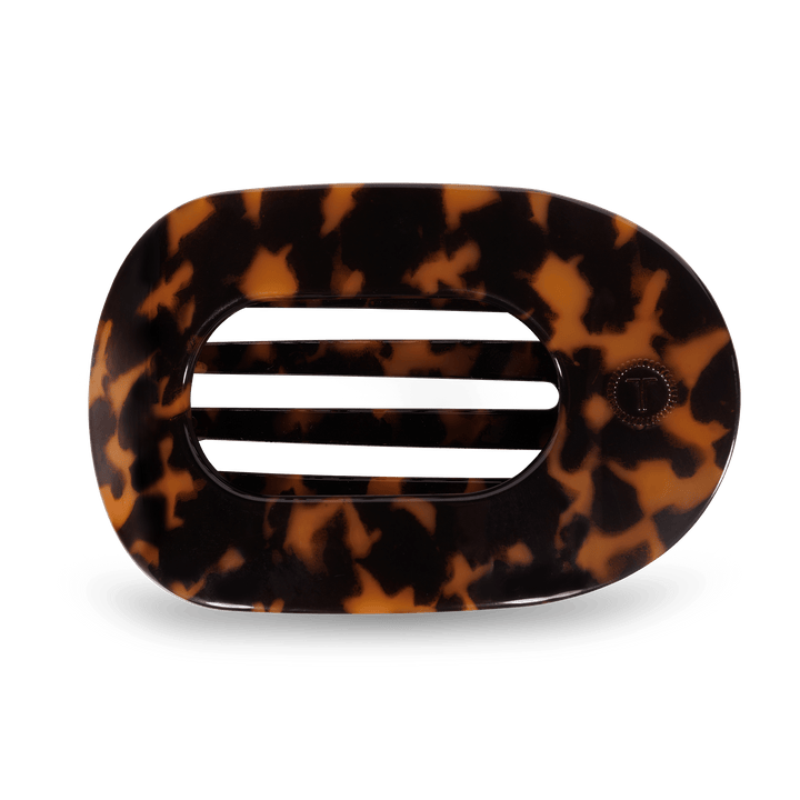 Oval tortoiseshell hair accessory featuring three horizontal slits and a subtle T logo on the right side