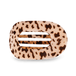 Oval acetate hair claw clip featuring a cream and dark brown cow print design with five internal horizontal slats