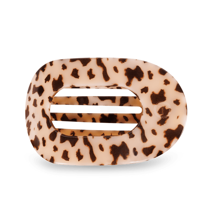 Oval acetate hair claw clip featuring a cream and dark brown cow print design with five internal horizontal slats