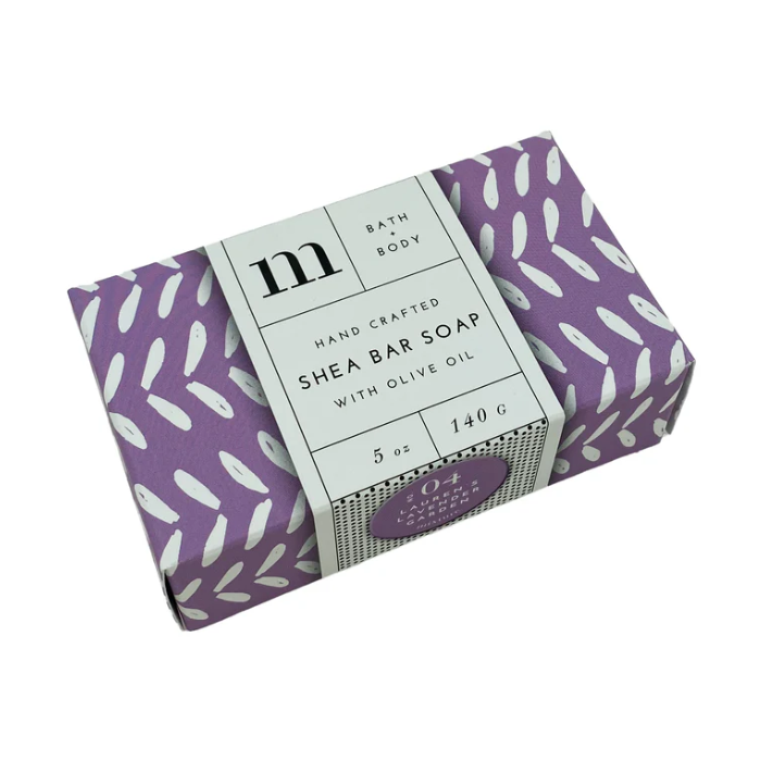 Hand Crafted Shea Bar Soap with Olive Oil in a lavender purple box featuring white abstract marks and a white label detailing 'm BATH + BODY' and 'LAUREN'S LAVENDER GARDEN'