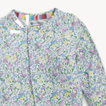 Eco-friendly child's long-sleeved top featuring a delicate all-over floral print in pastel pink, yellow, and blue on a white background, with a vibrant rainbow-striped inner collar