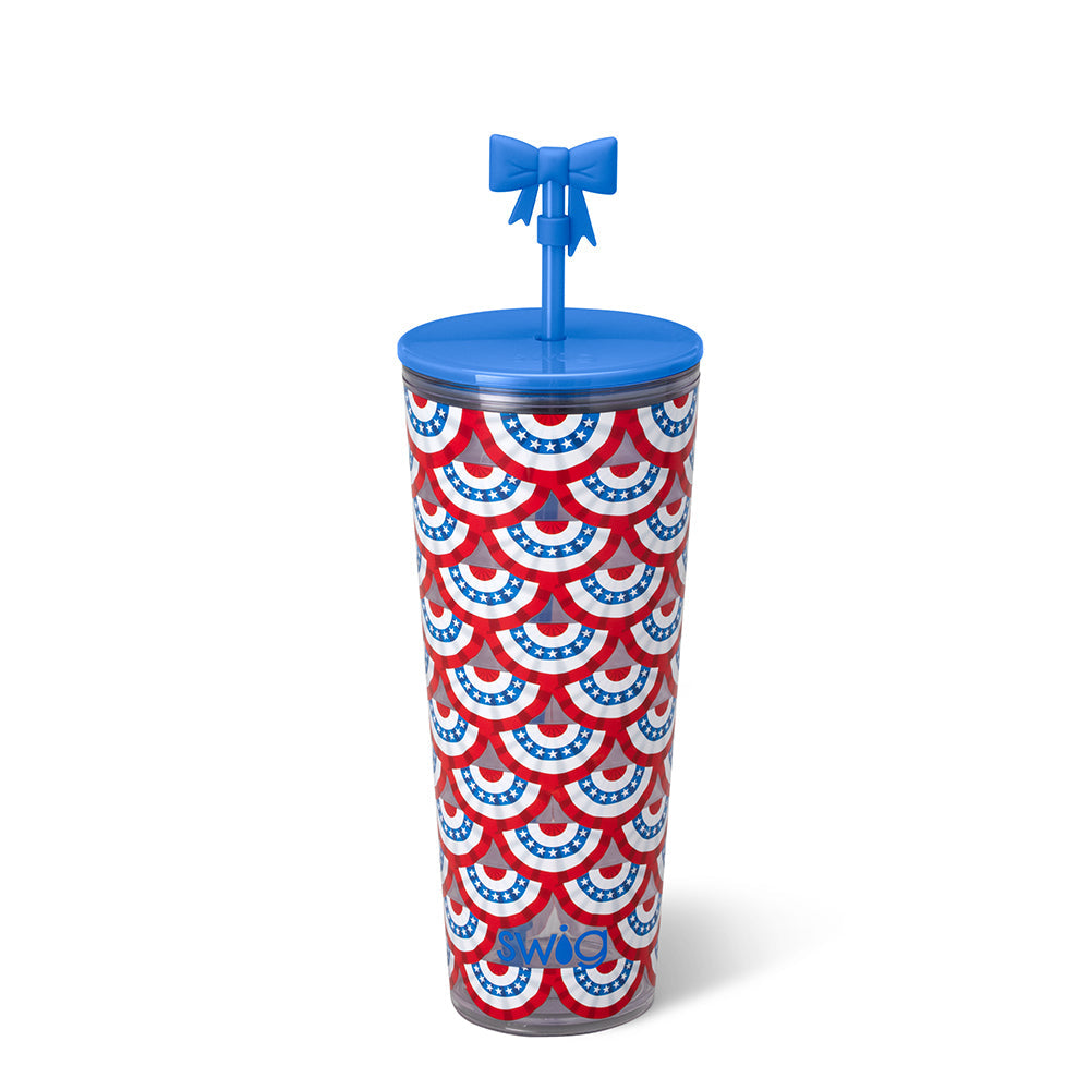 Product photography by Swig Life of a patriotic-themed tumbler featuring a scalloped red, white, and blue star-spangled bunting pattern, a solid blue lid, and a matching straw topped with a decorative blue bow topper