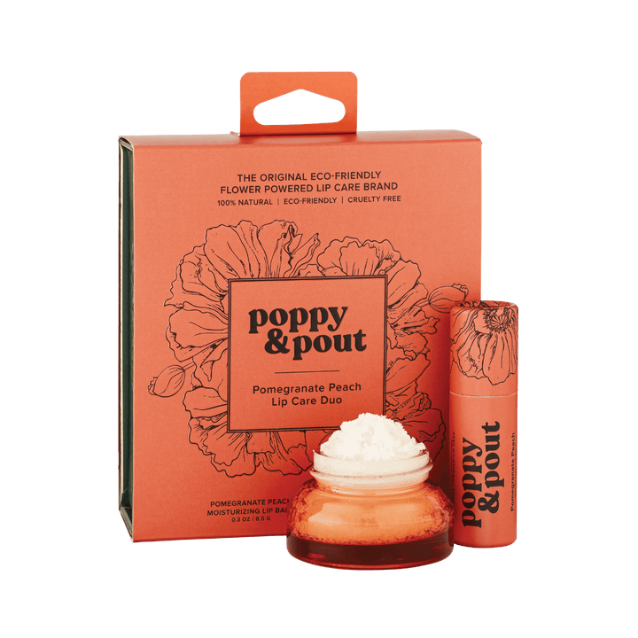 Product photography of Poppy & Pout Pomegranate Peach Lip Care Duo on a dark green background featuring a coral orange box with black poppy floral designs, a matching lip balm stick, and a small amber jar with white product, highlighting its eco-friendly flower-powered branding