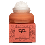 Product photography of an open amber jar of Poppy & Pout Pomegranate Peach Exfoliating Lip Scrub with white sugar scrub overflowing, resting on its coral box decorated with black poppy flowers