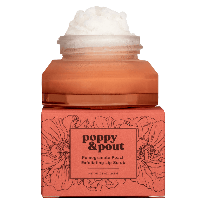 Product photography of an open amber jar of Poppy & Pout Pomegranate Peach Exfoliating Lip Scrub with white sugar scrub overflowing, resting on its coral box decorated with black poppy flowers