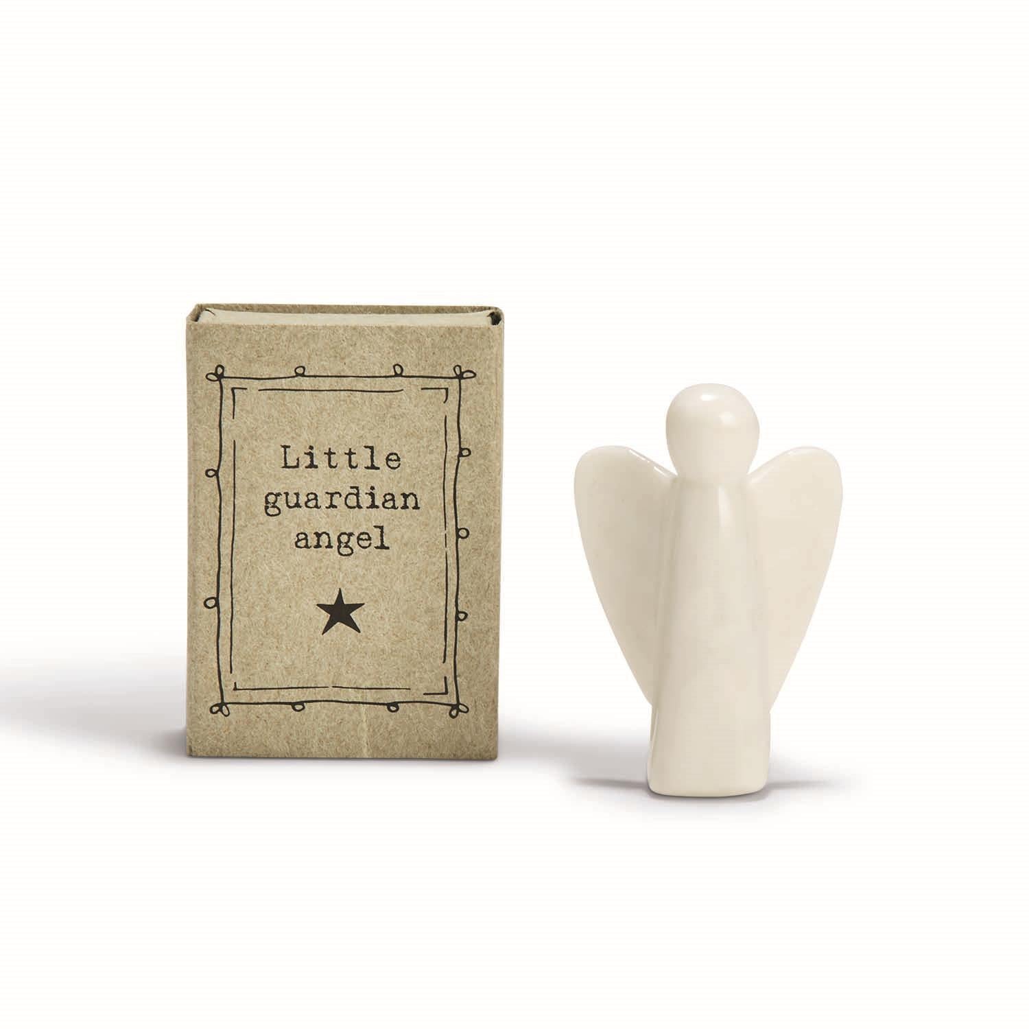 Small white ceramic angel figurine next to a cardboard box labeled Little guardian angel