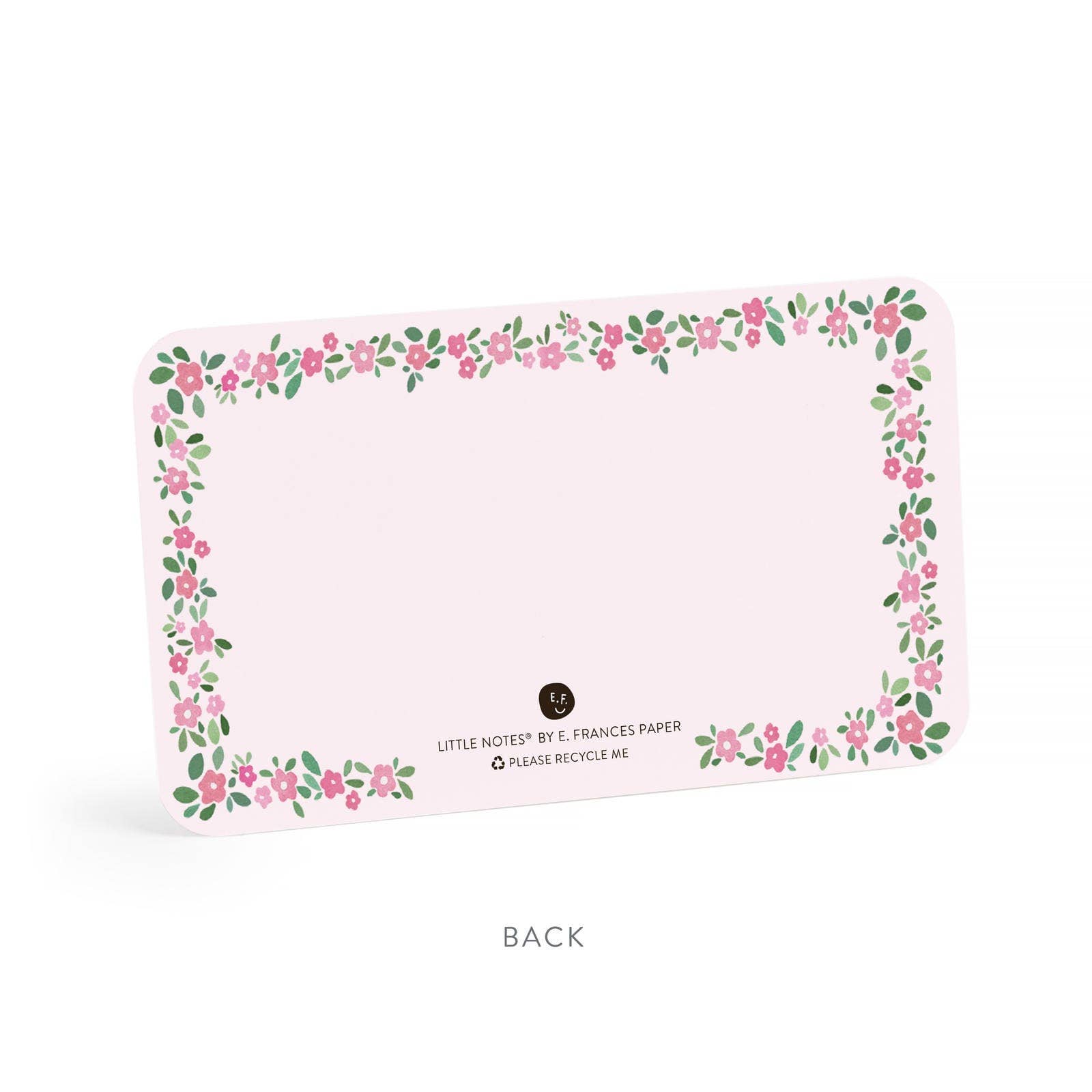 Paper note card by E. Frances Paper, the back of a light pink note card features a charming floral border of scattered pink flowers and green leaves along with the text LITTLE NOTES® BY E. FRANCES PAPER and an E.F. logo with a smiling face