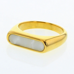 Jewelry: A sleek gold ring featuring a rectangular iridescent mother-of-pearl inlay against a white background