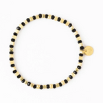 Black and gold beaded stretch bracelet with alternating faceted black beads and textured gold beads featuring a small round gold charm with initials on a white background