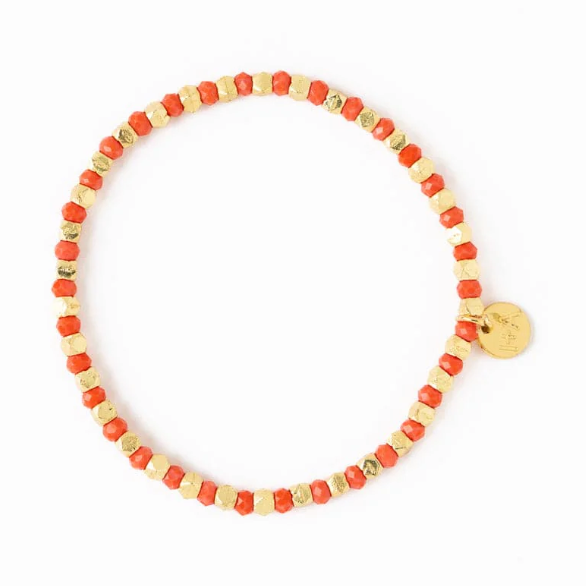 Beaded bracelet with alternating coral red faceted beads and irregular gold beads featuring a small round gold logo charm on a white background