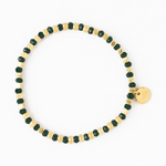 A gold and dark green beaded bracelet featuring alternating faceted beads and a small round gold charm with an etched design