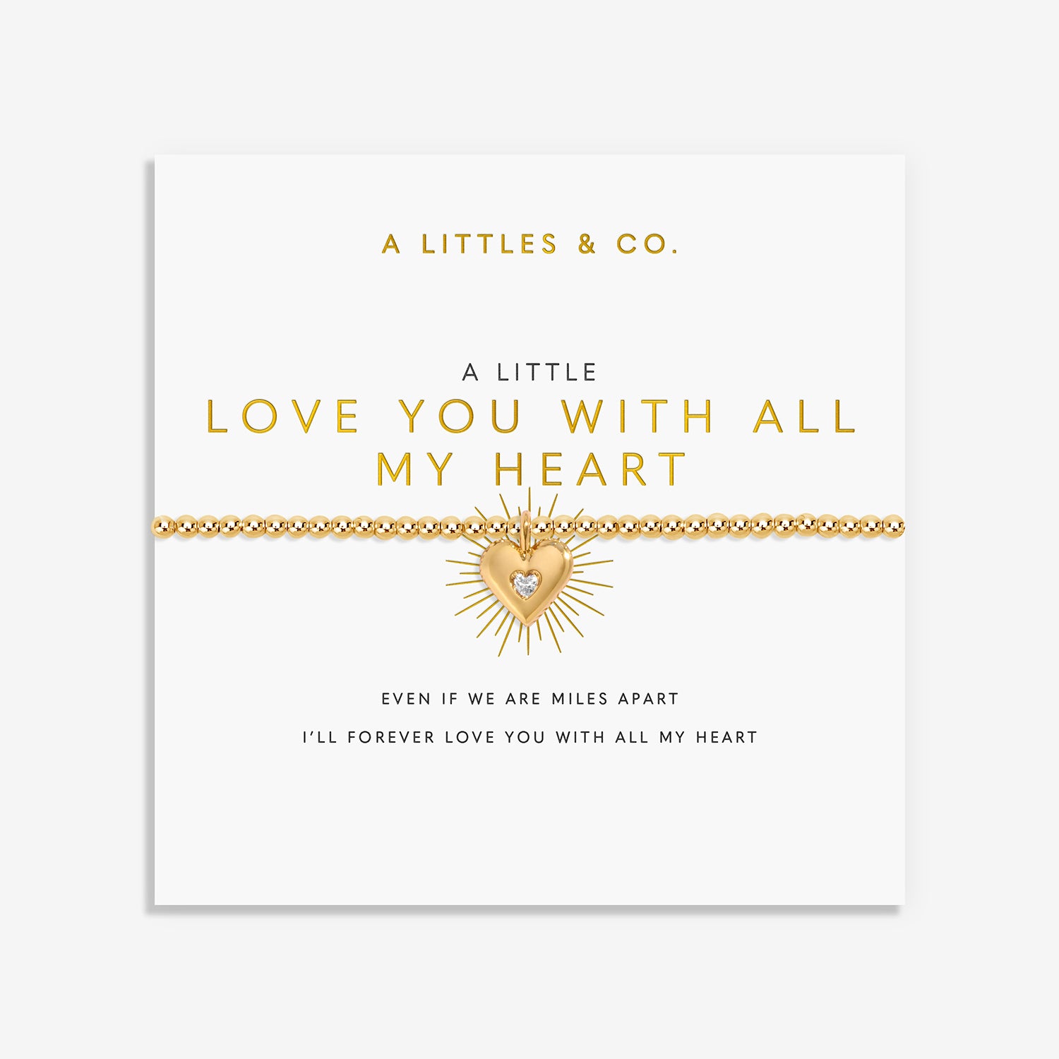 Gold beaded bracelet with a sunburst heart charm on a display card