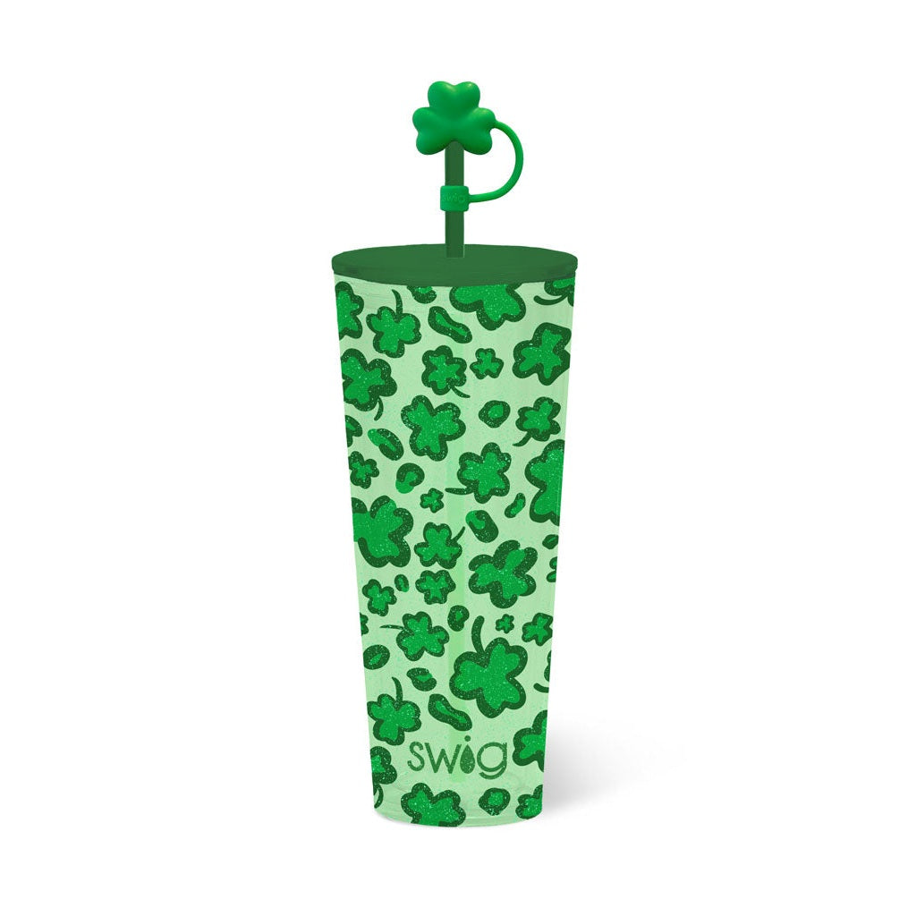 Product photograph of a green Swig insulated tumbler featuring a glittery shamrock pattern, a dark green lid, and a prominent shamrock-shaped straw topper