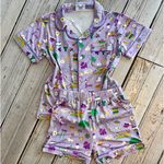 Lavender pajama set with a vibrant New Orleans Mardi Gras print showcasing NOLA text, iconic streetcars, and festive masks and beads