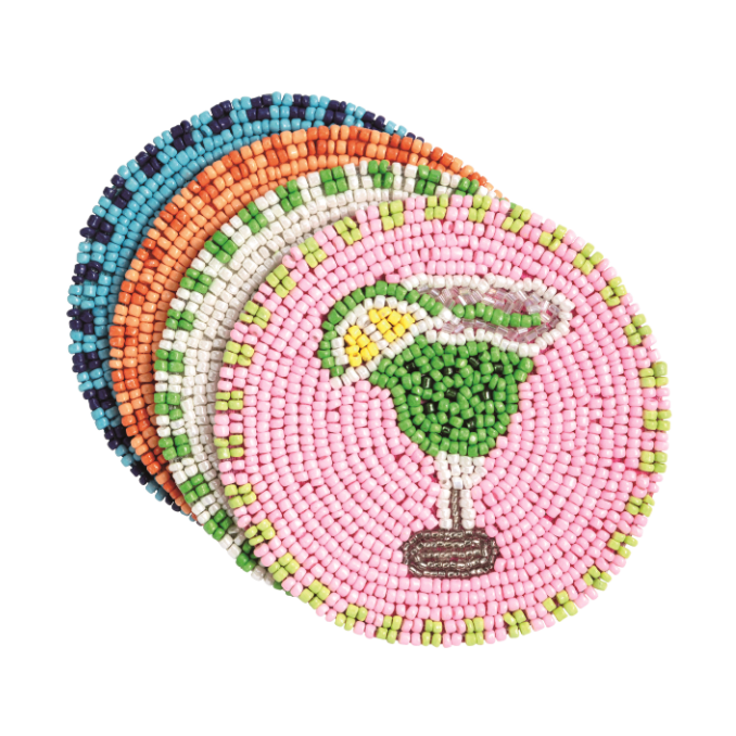 A stack of beaded fabric round coasters, with the top one displaying a pink background and a green margarita glass with yellow lime and white rim, revealing vibrant light blue, orange, and white-green patterned coasters underneath