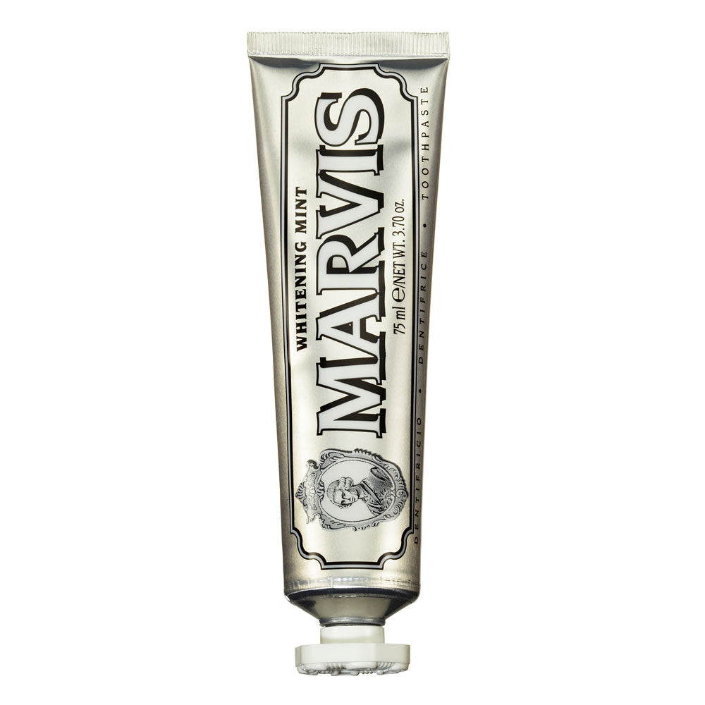 Studio product photography by Marvis of a Whitening Mint toothpaste tube centered on a white background featuring its signature silver metallic finish, bold vintage-style black typography, and an intricate decorative portrait crest