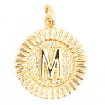 Gold pendant featuring a circular initial M charm with a textured center, a ridged fluted border, and an attached top loop