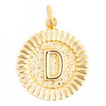 Photograph of a round golden initial D pendant featuring a hammered texture behind the letter and a fluted outer rim with a small bail loop