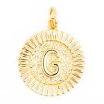 A shiny gold initial G medallion pendant with a raised capital G, radial fluted border, and hammered texture