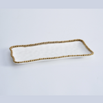 White rectangular ceramic serving tray with a distinctive gold beaded rim and slightly undulating edges on a clean white background