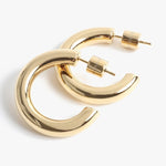 Gold earrings by Stella McCartney, a pair of shiny polished chunky C-shaped hoop earrings featuring Stella McCartney engraved earring backs