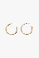 A pair of shiny thick gold hoop earrings with stud closures displayed against a plain white background