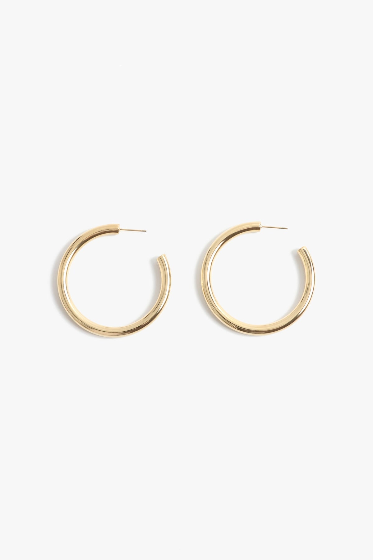 A pair of shiny thick gold hoop earrings with stud closures displayed against a plain white background