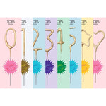Gold glitter number and shape sparkler candles on colorful backgrounds