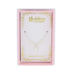 Product photography by Golden by Jane Marie showing a silver-toned cross necklace with small pearl beads presented in a pink and gold scrolled gift box featuring '18K GOLD PLATED' text
