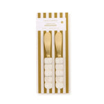 Product photography of Two's Company Modern Pop Spreaders featuring a pair of gold-finished stainless steel knives with white marbled resin bubble-textured handles displayed on a gold and white striped card