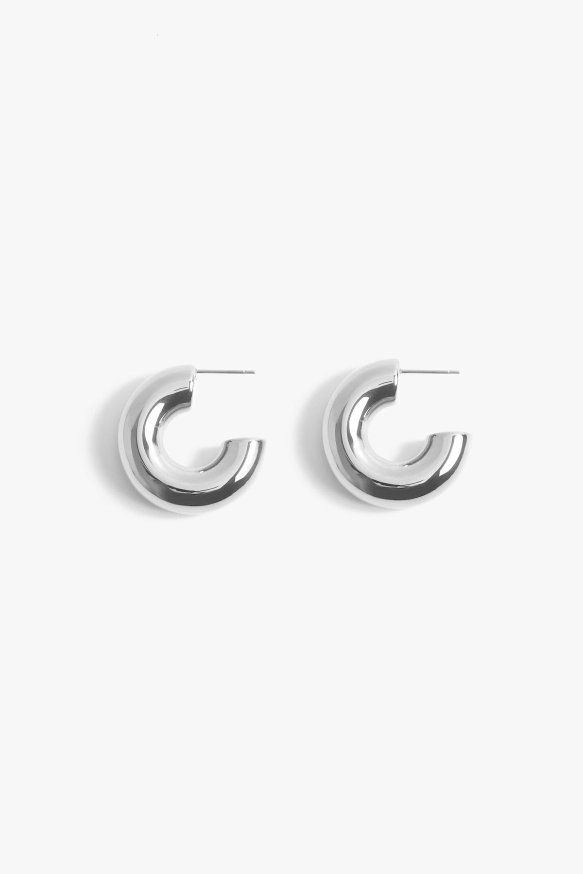 A pair of polished silver chunky hoop earrings with a minimalist design against a white background