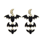 A pair of dangling earrings featuring gold crescent moons and three descending black glittery bats with gold outlines