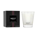 NEST New York Moroccan Amber scented candle featuring a black box with vertical purple and gold stripes and a clear glass holder with etched white stripes displaying the NEST logo and white wax