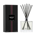 NEST New York Moroccan Amber reed diffuser product photography featuring a clear square glass bottle with black reeds and ribbed detail beside its black rectangular box with a vertical purple striped pattern