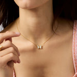 Gold chain necklace with a small white butterfly pendant worn on a neck