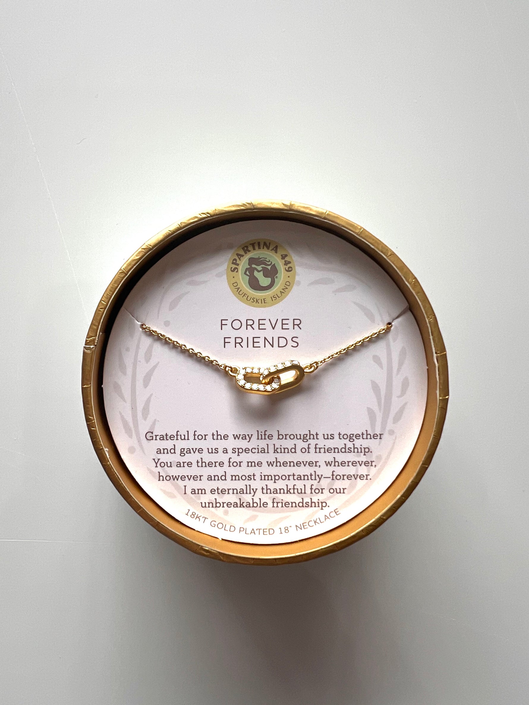 18KT gold-plated necklace by Spartina 449 featuring interlocking pave-set cubic zirconia links presented in a round gold-rimmed gift box with a pink insert bearing Forever Friends text and a mermaid logo